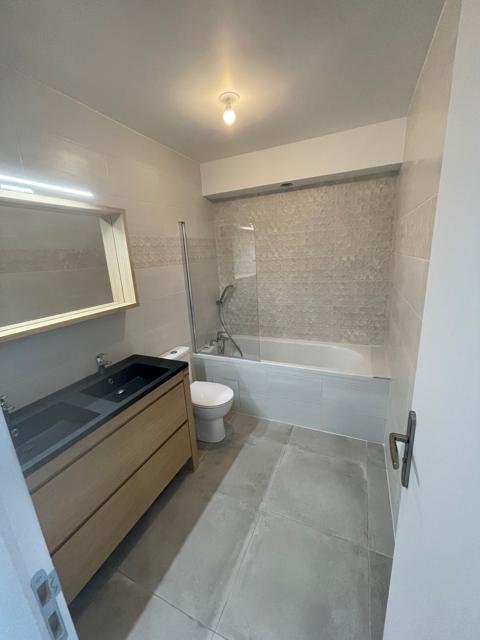 Salle de bain avec baignoire, double vasque et grand miroir