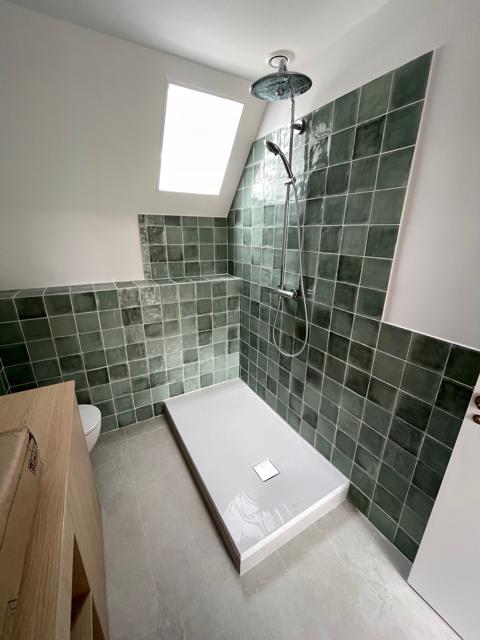 Douche avec carreaux verts et fenêtre de toit