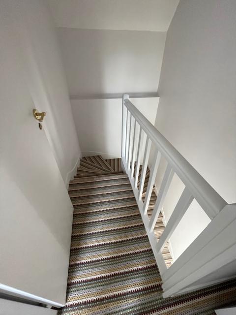 Escalier avec moquette rayée et garde-corps blanc